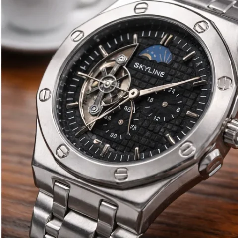 Reloj automático Skyline Eclipse de acero con esfera negra junto a una taza de café.