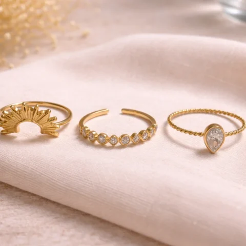 conjunto de anillos dorados elegantes en mano con diseño sol y circonitas