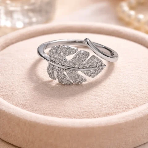 Anillo hoja plateado con circonitas sobre base de terciopelo elegante