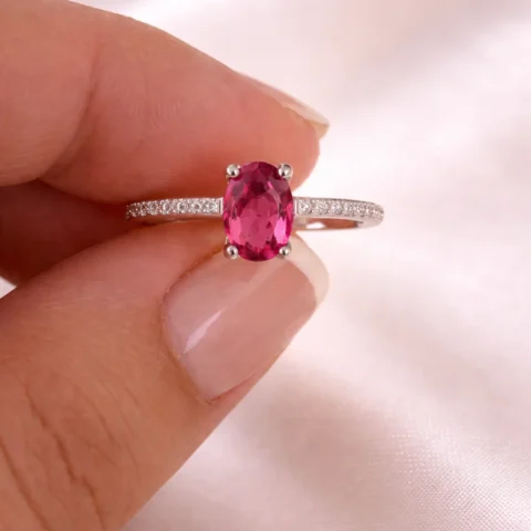 Anillo Luma Rose sujetado entre los dedos con piedra rosa oval