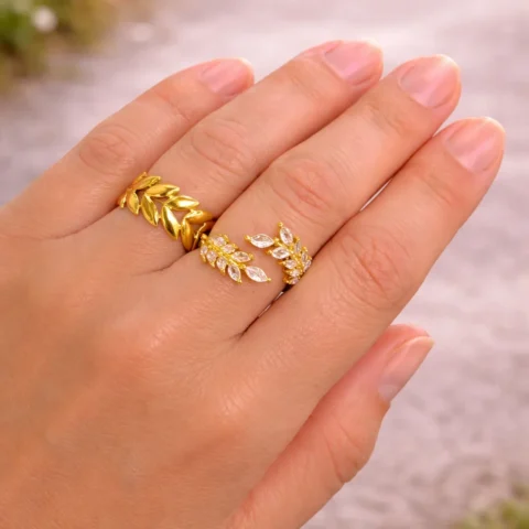 Anillo Eden dorado con hojas y circonitas en mano con luz natural