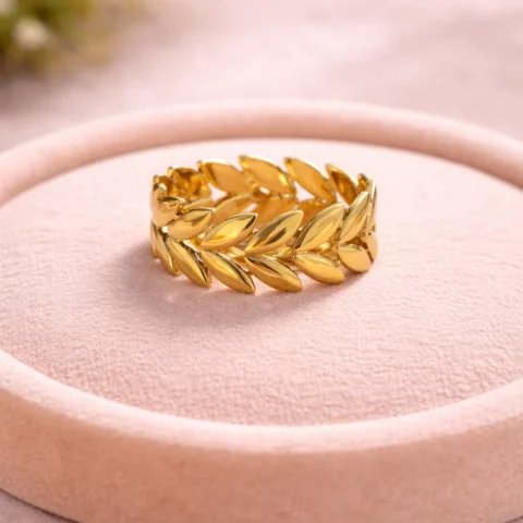 Anillo Laurel dorado con diseño de hojas sobre base de terciopelo en escaparate elegante