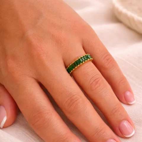anillo verde dorado Viridia en mano detalle piedras verdes baguette