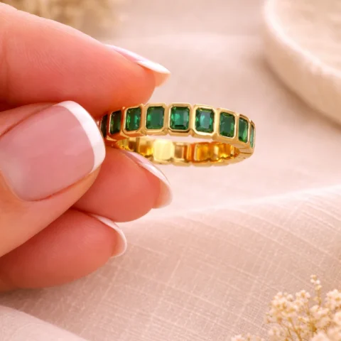 Anillo Viridia Square dorado con piedras verdes puesto en la mano
