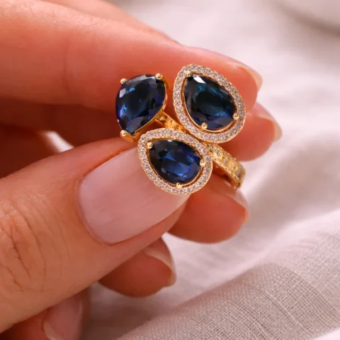 anillo dorado con piedras azules puesto en mano mujer