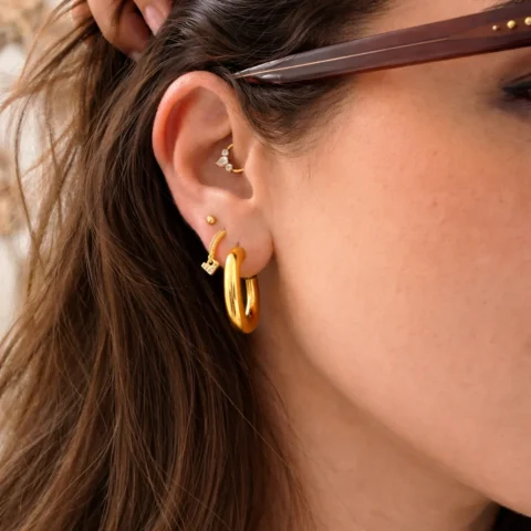 Aros Alba dorados puestos en oreja look elegante