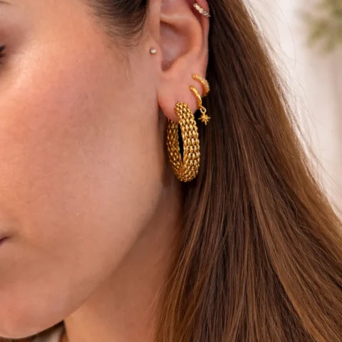 aros dorados Nexus puestos en oreja con estilo moderno