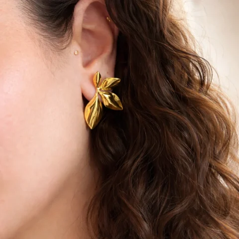 pendientes orquídea dorados puestos en oreja diseño floral elegante