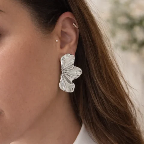 pendientes pétalos plateados de acero inoxidable puestos en la oreja