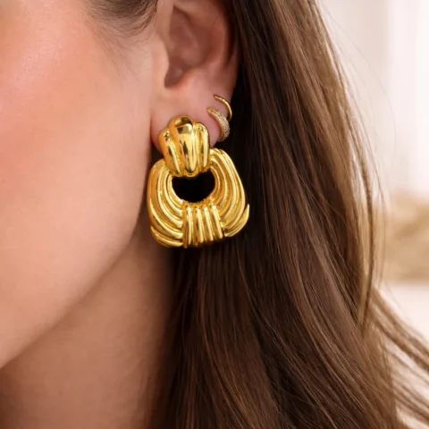 pendientes Lumen dorados puestos en oreja mujer