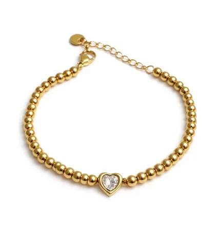 Pulsera Corazón Alba dorada con cuentas y corazón con zirconia sobre fondo blanco.