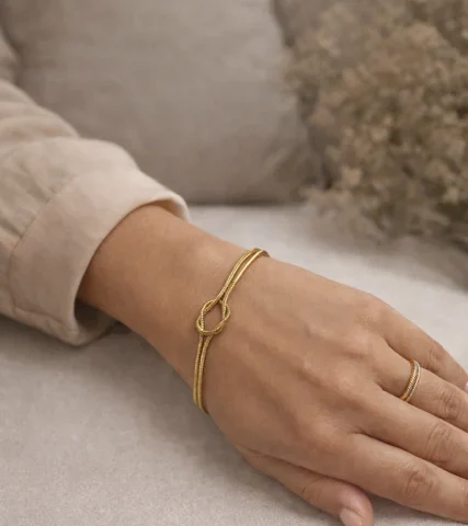 Pulsera Lazo Amor de acero inoxidable dorado con doble cadena y nudo central de Inaya Complementos.