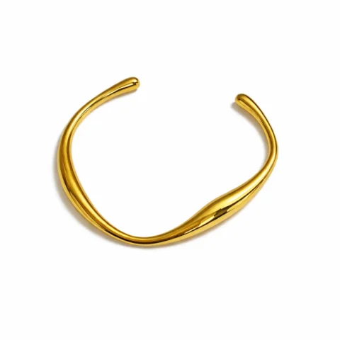 Pulsera rígida abierta dorada de acero inoxidable con diseño minimalista y acabado brillante sobre fondo blanco.