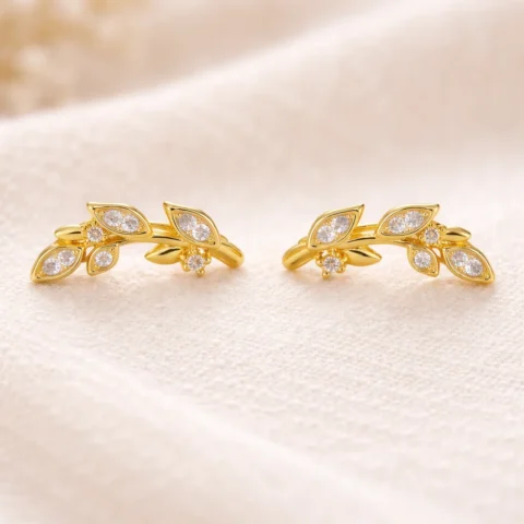 pendiente trepador leaf dorado con circonitas sobre fondo natural elegante