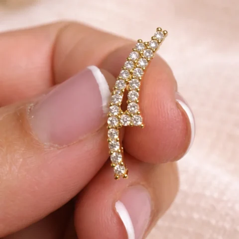 pendientes trepadores Shine dorado sostenidos en la mano detalle