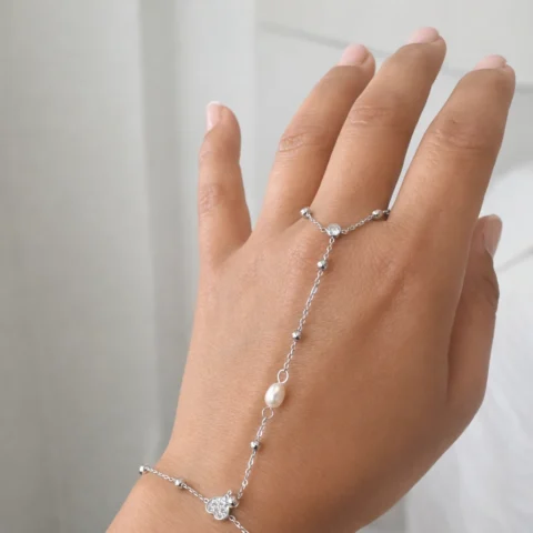 Pulsera de mano Manus Perla plateada con perla en mano fondo elegante