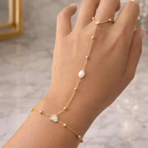 Pulsera de mano Manus Perla dorada con perla en mano fondo elegante