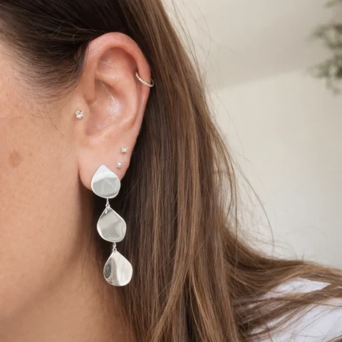 pendientes gota fluida plateado puestos en oreja mujer