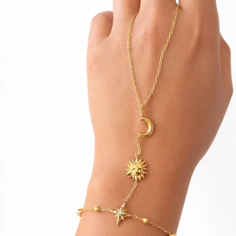 Pulsera de mano Manus Celeste dorada con luna sol y estrella sobre fondo blanco