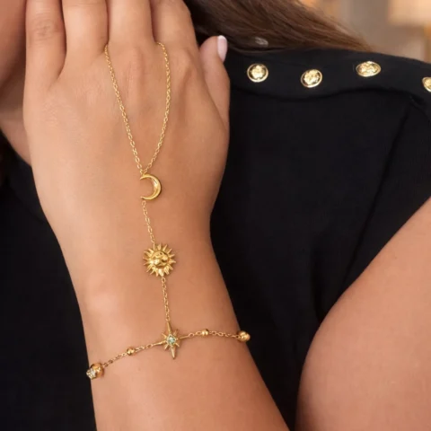 Pulsera de mano Manus Celeste dorada con detalles celestiales en mano fondo elegante