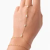 Pulsera de mano Manus Elara dorada con circonitas alineadas sobre fondo blanco
