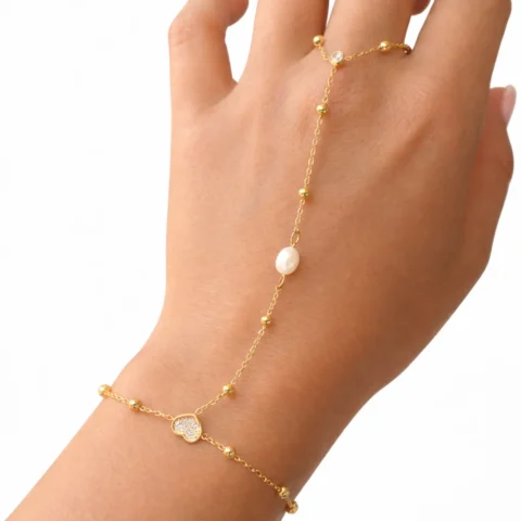 Pulsera de mano Manus Perla dorada con perla central sobre fondo blanco