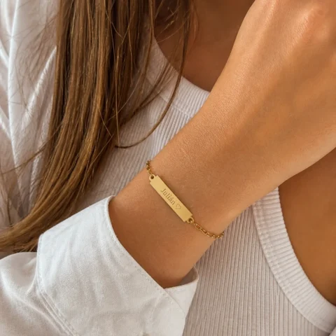 Pulsera dorada personalizada Nexo Identidad en muñeca de mujer joven con placa grabada